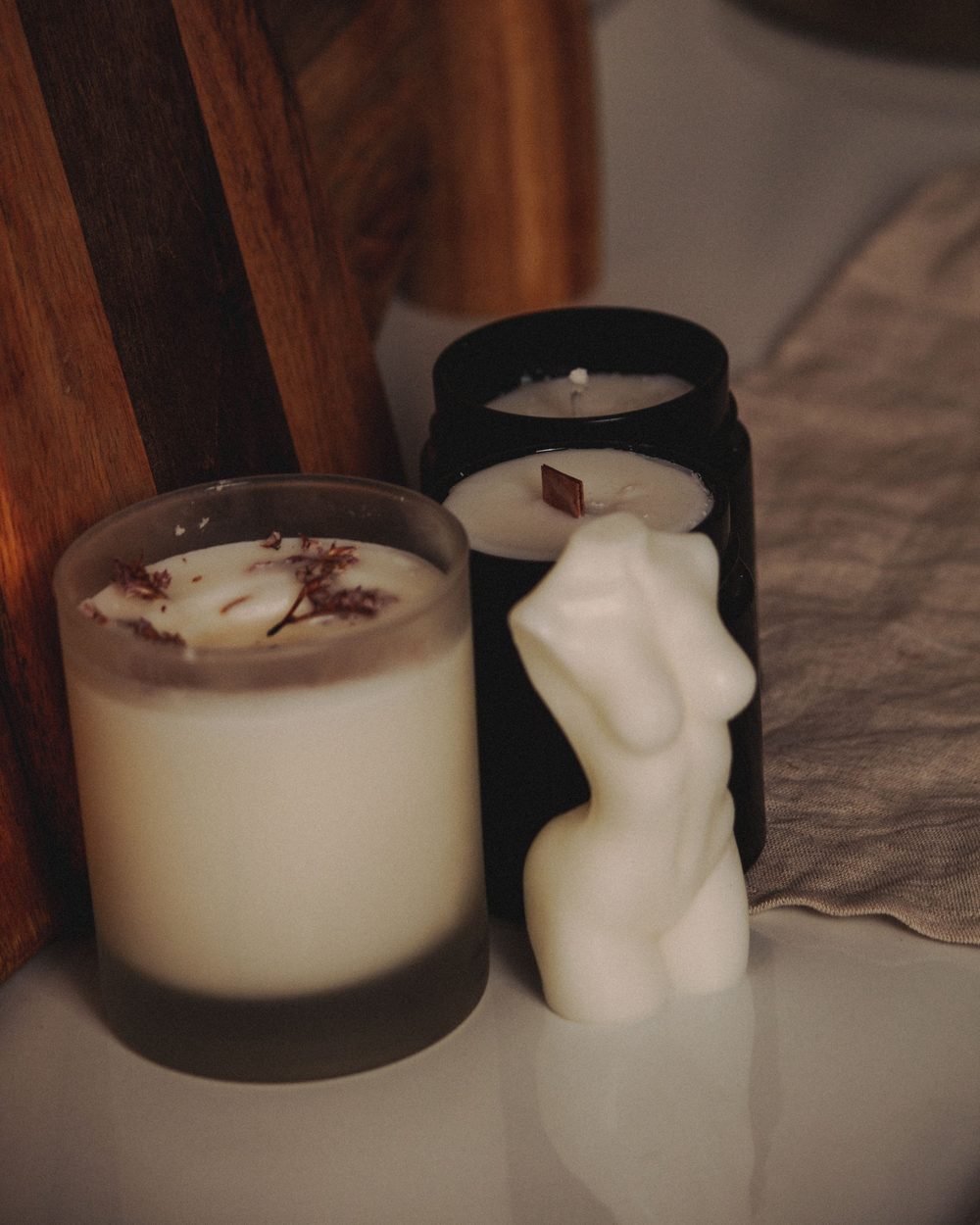 A frosted jar candle beside a sculpted candle
