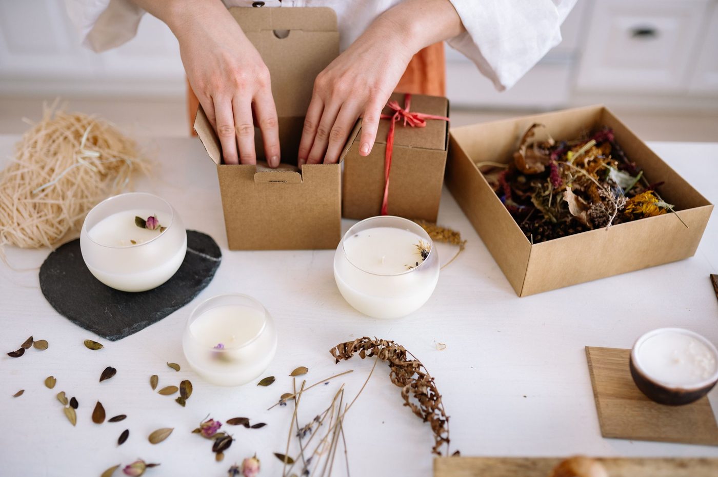 Handmade candles being packed into gift boxes with dried flowers
