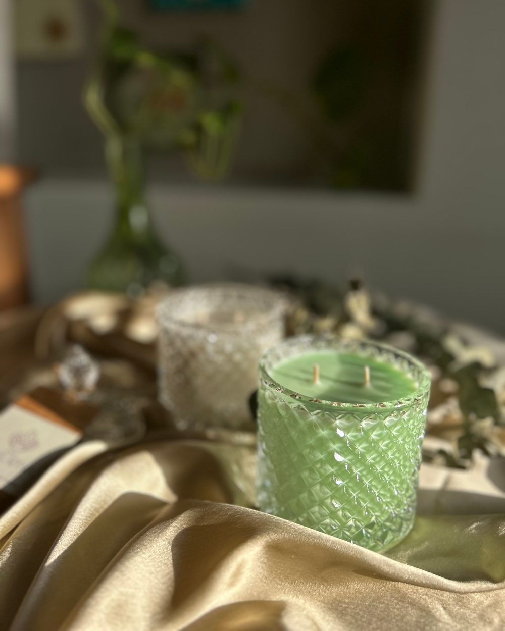 A green candle in a cut-glass jar on gold satin