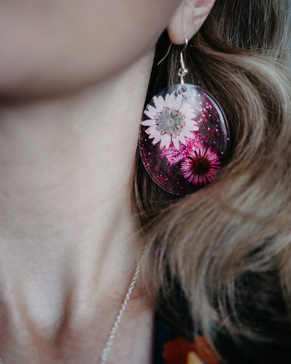 A round resin earring with pink flowers inside