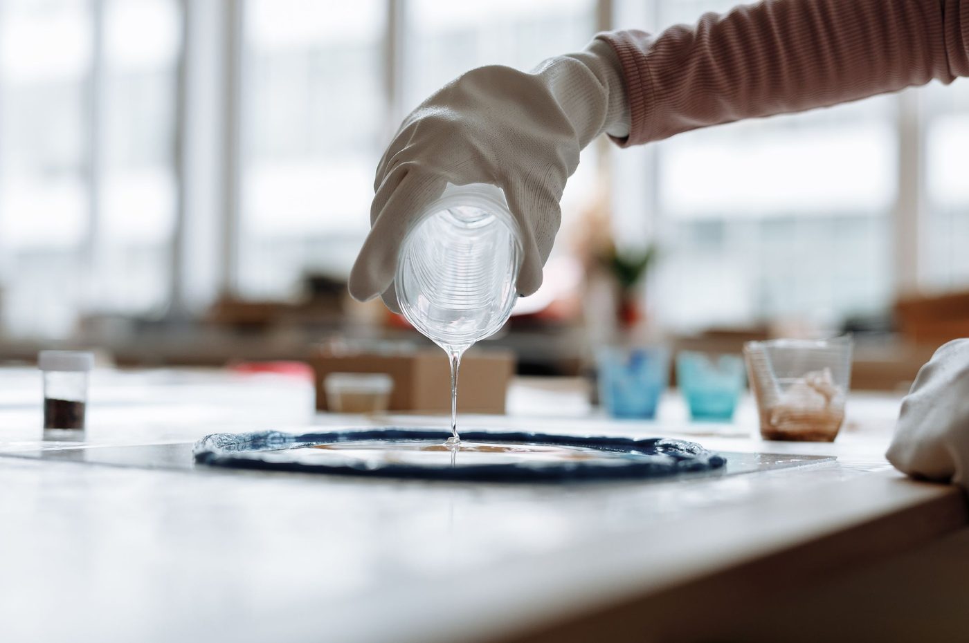 Clear resin being poured over a blue piece on a workbench